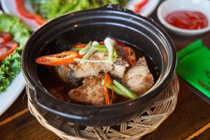 a black bowl of food with vegetables and meat at Hodota Cam Bình Resort & Spa - Lagi Beach in Vĩnh Thạnh