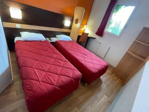 duas camas num pequeno quarto com cobertores vermelhos em Premiere Classe Rungis - Orly em Rungis
