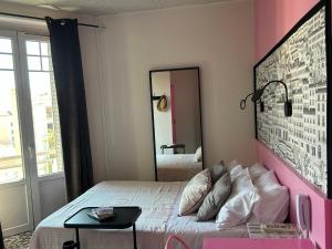 a pink bedroom with a bed and a mirror at H&ocirc;tel de la Croix-Rousse in Lyon