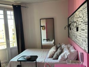 リヨンにあるオテル デ ラ クロワ ルースのピンクのベッドルーム(ベッド1台、鏡付)