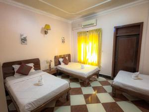 a room with two beds and a window at Nawin Palace Guesthouse in Phnom Penh