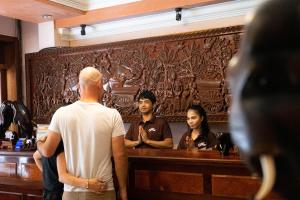 a man standing in front of a wooden wall with people at Nawin Palace Guesthouse in Phnom Penh