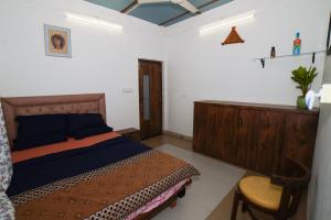 a bedroom with a bed and a chair in it at 6Tamarind in Gholvad