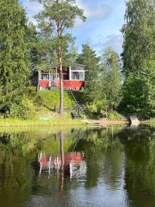 a house on a hill next to a body of water at Two bedroom cottage with peaceful views in Jyväskylä