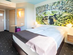 une chambre d'hôtel avec un lit et un tableau sur le mur dans l'établissement B&B Hotel Karlsruhe, à Karlsruhe