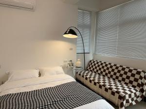 um quarto com uma cama, um candeeiro e um sofá em Qiestop B&B em Jinning
