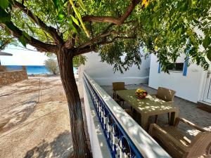 a table and chairs under a tree on the beach at Stella Beach House in Archangelos