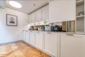 a kitchen with white cabinets and a wooden floor at Westminster Fire Station Luxury Apartments in London
