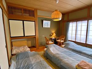 a bedroom with two beds and a table and chairs at Guesthouse Imaichi ゲストハウス今市マチナカ in Nikko