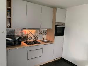 a kitchen with white cabinets and a sink and a microwave at Ferienwohnung Gabriel in Kirchentellinsfurt