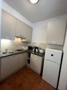 een keuken met witte kasten, een wastafel en een koelkast bij Garay Utca - Unit A52 in Boedapest
