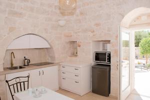 eine Küche mit weißen Schränken und einer Steinmauer in der Unterkunft Trullo Cinquenoci Suite in Locorotondo