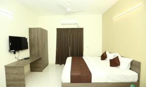 um quarto com uma cama e uma televisão de ecrã plano em FabHotel I Live Inn em Chennai