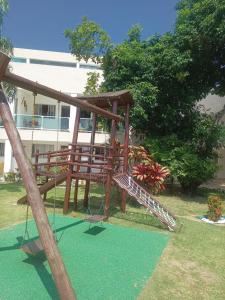 un parque infantil de madera con columpio en un patio en Bella casa 10 em Guarajuba, apartamento equipado para você e sua família, tudo que você precisa pra se sentir em casa! en Guarajuba