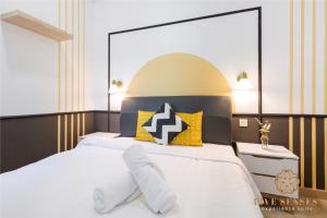 a bedroom with a white bed with yellow and black pillows at The Colony & Luxe, KLCC by Five Senses in Kuala Lumpur