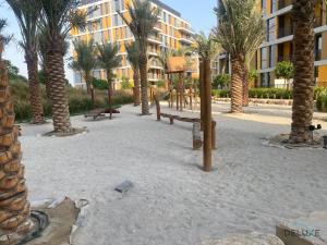 a playground with palm trees in front of a building at Exquisite 2BR with Assistant Room at Mesk 1 Midtown Dubai Production City by Deluxe Holiday Homes in Dubai