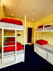 Mitra Hostel Sonamarg في سونامارج: غرفة مع ثلاثة أسرة بطابقين مع ملاءات حمراء