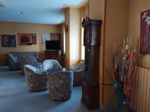 - un salon avec des chaises et une horloge grand-père dans l'établissement Hotel Sommeiller, à Bardonnèche