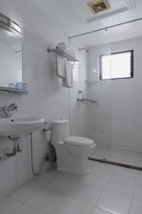 a white bathroom with a toilet and a shower at Hotel Ratnasambhava in Lumbini