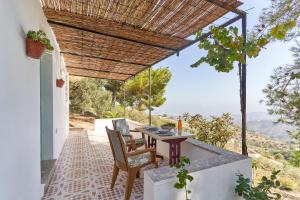 a patio with a table and chairs under a roof at Cortijo de Arriba in Frigiliana
