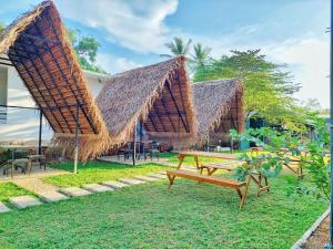two picnic tables with straw umbrellas in a yard at Catch Up Dambulla in Dambulla