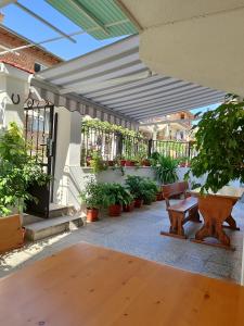 a patio with awning and benches and potted plants at Milchevi Guesthouse in Sozopol