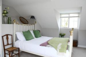 a white bed with green pillows in a bedroom at Spring Cottage,Gorgeous and Hi-spec in Kilkhampton
