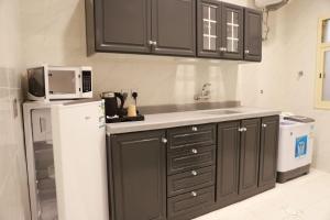 eine Küche mit schwarzen Schränken und einem weißen Kühlschrank in der Unterkunft فندق المساء in Abha
