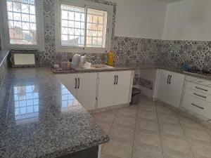 uma cozinha com armários brancos e uma bancada em mármore em dari darkom em Kerkouene