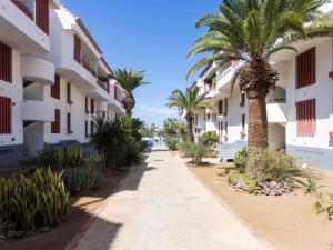 a street in front of a building with palm trees at Apartment Edificio Altemar in Playa de las Americas