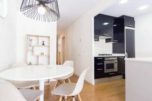 una cucina e una sala da pranzo con tavolo e sedie bianchi di L'alzina Apartment a Barcellona