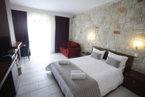 a bedroom with a large bed and a red chair at Nostos Hotel in Afitos