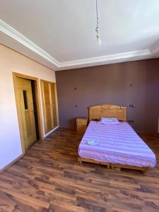 um quarto com uma cama e piso em madeira em Villa haut standing dans une résidence fermée em Zaouia Sidi Rahkal