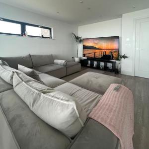 a living room with a couch and a tv at Seafront apartment with spectacular views in Porthcawl