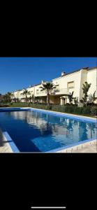 a large blue swimming pool in front of a building at Villa haut standing dans une résidence fermée in Zaouia Sidi Rahkal