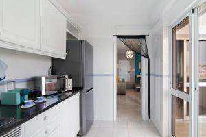 una cucina con mobili bianchi e un forno a microonde di Blue House ad Armação de Pêra