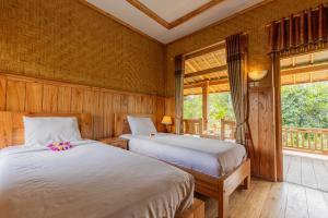 two beds in a room with wooden walls and windows at Mulia Garden Bungalows in Tabanan