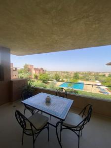 a table and chairs on a balcony with a view of a pool at Marrakech - Prestigia Golf - haut standing in Marrakesh