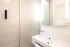 La salle de bains est pourvue d'un lavabo blanc et d'un miroir. dans l'établissement B&B HOTEL Besançon Valentin, à Besançon