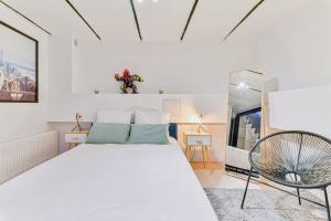 a white bedroom with a large bed and a chair at Renovated Design Apartment In Montparnasse in Paris