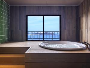 TWIN LINE HOTEL YANBARU OKINAWA JAPAN Formerly Okinawa Suncoast Hotel في ناغُو: حمام مع حوض مطل على المحيط