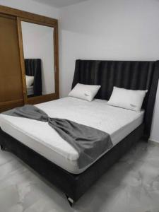 a bed with a black headboard and a mirror at Résidence Le Figuier Marako, Tizi-Gheniff in Tizi Gheniff