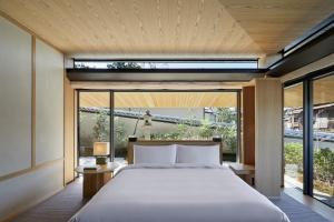 a bedroom with a large bed and large windows at Park Hyatt Kyoto in Kyoto