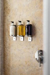 a bathroom wall with three soap dispensers on a wall at The House on the Pink Street in Lisbon in Lisbon