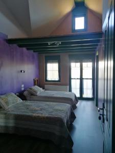 2 camas en una habitación con paredes y ventanas moradas en Hostería Casa Flor, en Murias de Rechivaldo