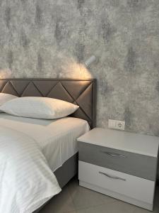 a bedroom with a bed with a headboard and a night stand at VIP Апартаменти подобово in Lutsk