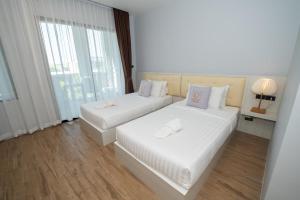 a bedroom with two beds with white sheets and a window at Guuden Huahin Hotel in Hua Hin +56 photos