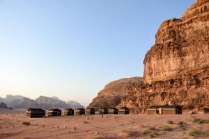 Wadi rum galaxy camp في وادي رم: مجموعة ملاجئ في الصحراء بجانب منحدر