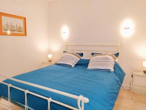ein Schlafzimmer mit einem blauen Bett mit Kissen in der Unterkunft Le Pouy, Jardin, Terrasse & Stationnement in Saint-Vincent-de-Paul