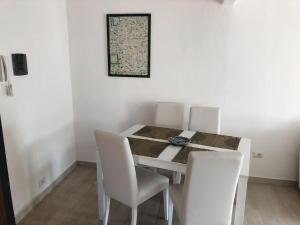 una sala da pranzo con tavolo e sedie bianche di Luis Apartment - Appartamento per single o coppia R7265 a Nuoro